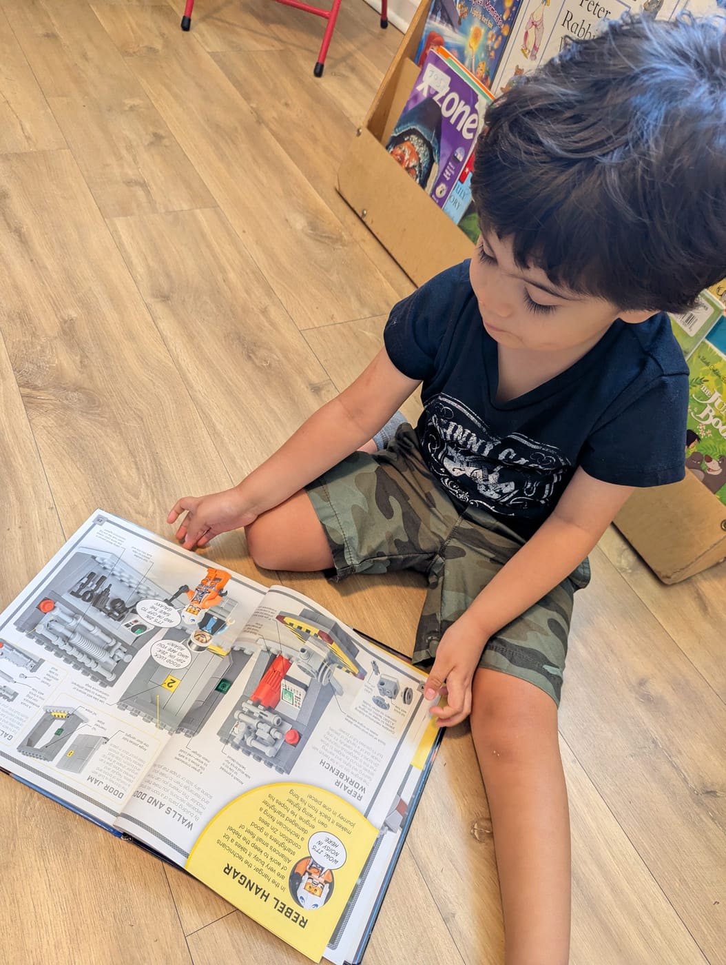A boy reading a building book on the classroom floor