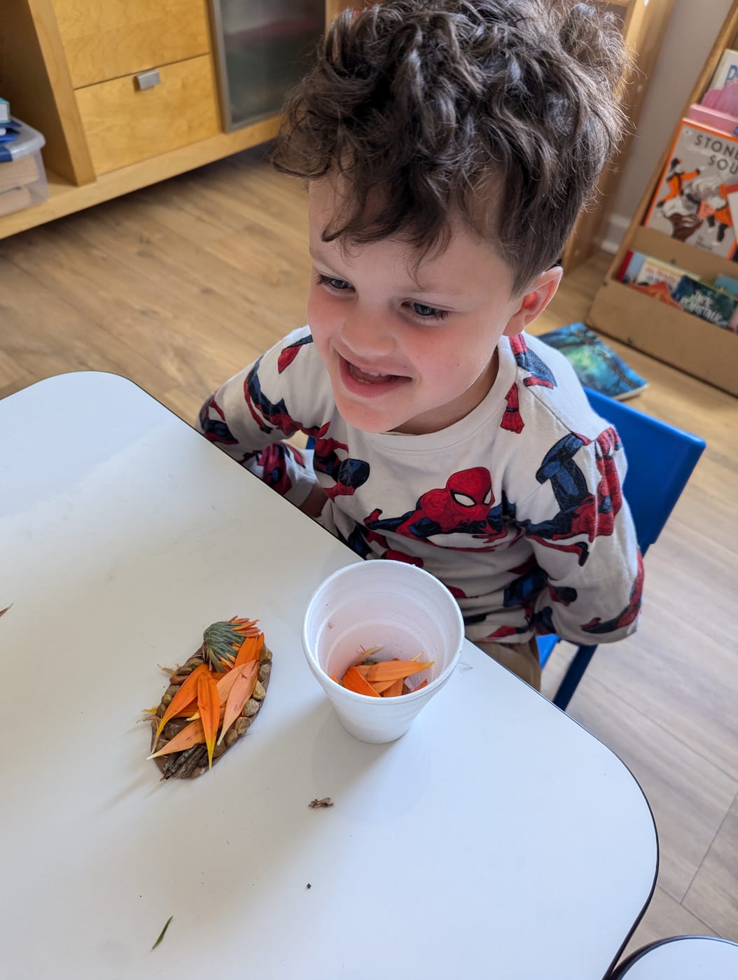 A smiling boy with his flower-petal nature collage